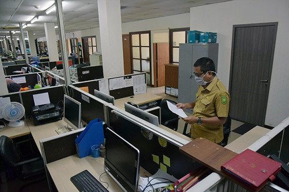 Remote work: A civil servant works during his in-office shift at the Riau Communication, Information and Statistics Agency in Pekanbaru on April 20, 2020 as his colleagues work from home.