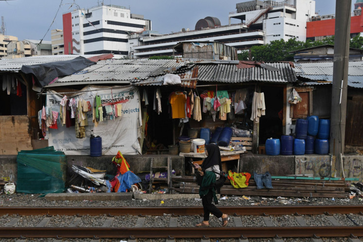 A woman walks on a railroad track alongside a slum in Kampung Bandan, Central Jakarta, on Oct. 14, 2022.