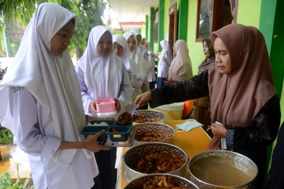 Students line up on March 5, 2024 to take part in a free school lunch pilot program at SMPN 1 Darul Imarah state junior high school in Aceh Besar, Aceh. The program budgeted a production cost of Rp 15,000 (92 US cents) per portion.