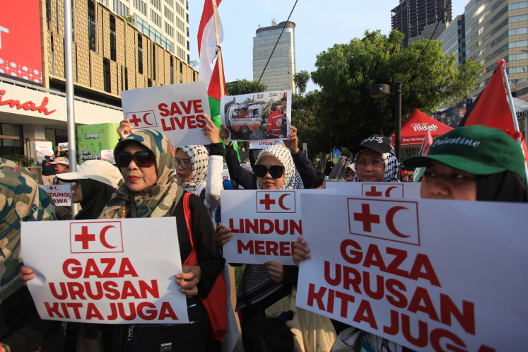 People hold posters that read “Gaza is also our business“ during a peaceful rally supporting Palestinians in Gaza in Jakarta on April 7, 2025. Medical workers, students and volunteers stage the rally to condemn the Israeli military's attack against medical personnel and hospitals in Gaza Strip.