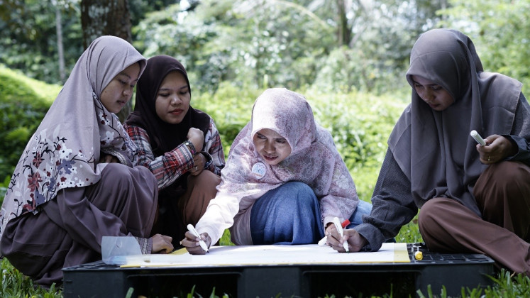 A group of women are photographed participating in the Bengkel Hijrah Iklim (BHI) 3.0 program, in which capacity building is conducted for young preachers to introduce them to the climate crisis and teach them about actions they can take as Islamic leaders in their respective communities.